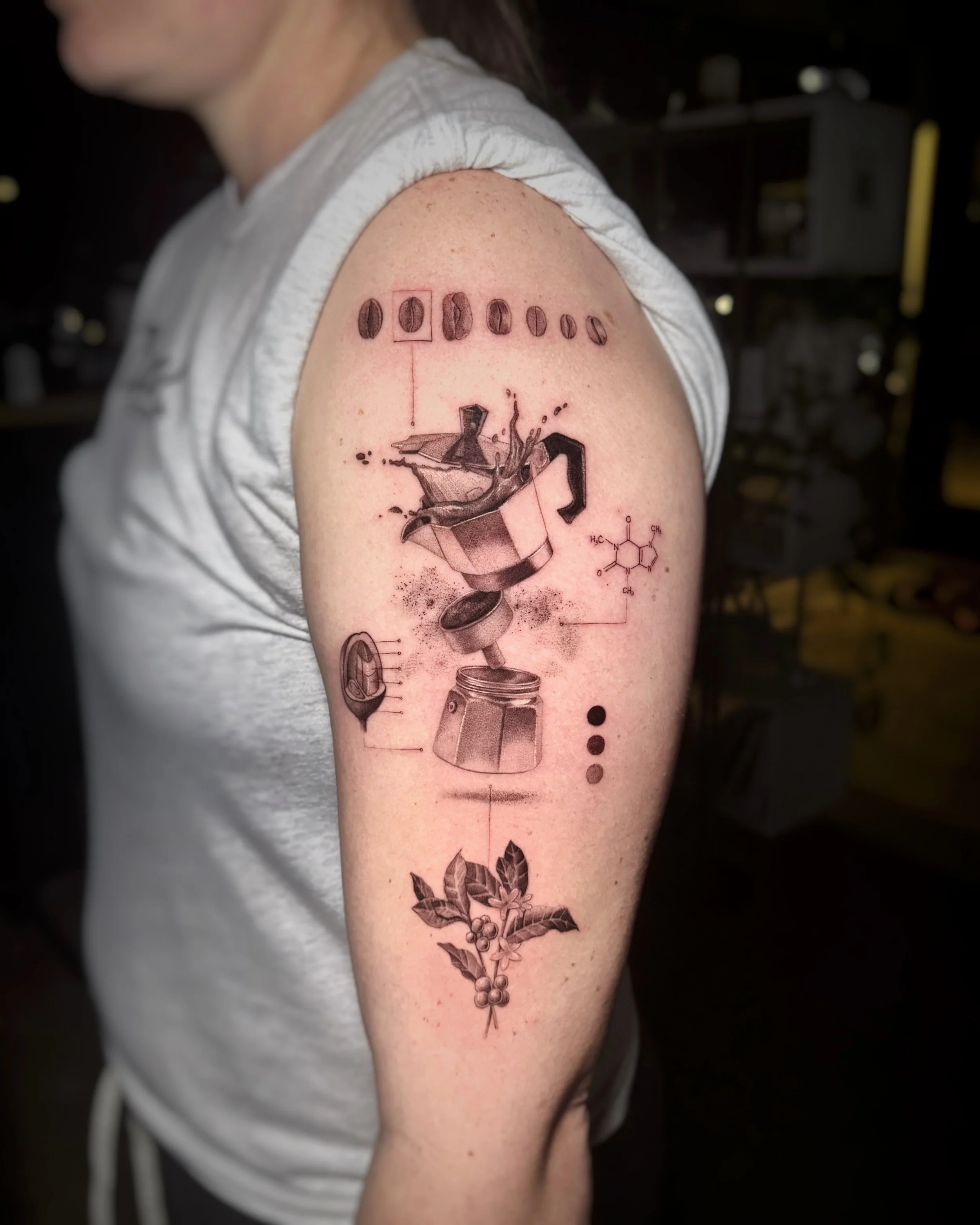 A hyper realistic tattoo done by Ihor (flowerhead.ink) on person's shoulder. Featuring a tribute to a coffee-making process - growing, flowering, roasting and coffee mocha pot. 