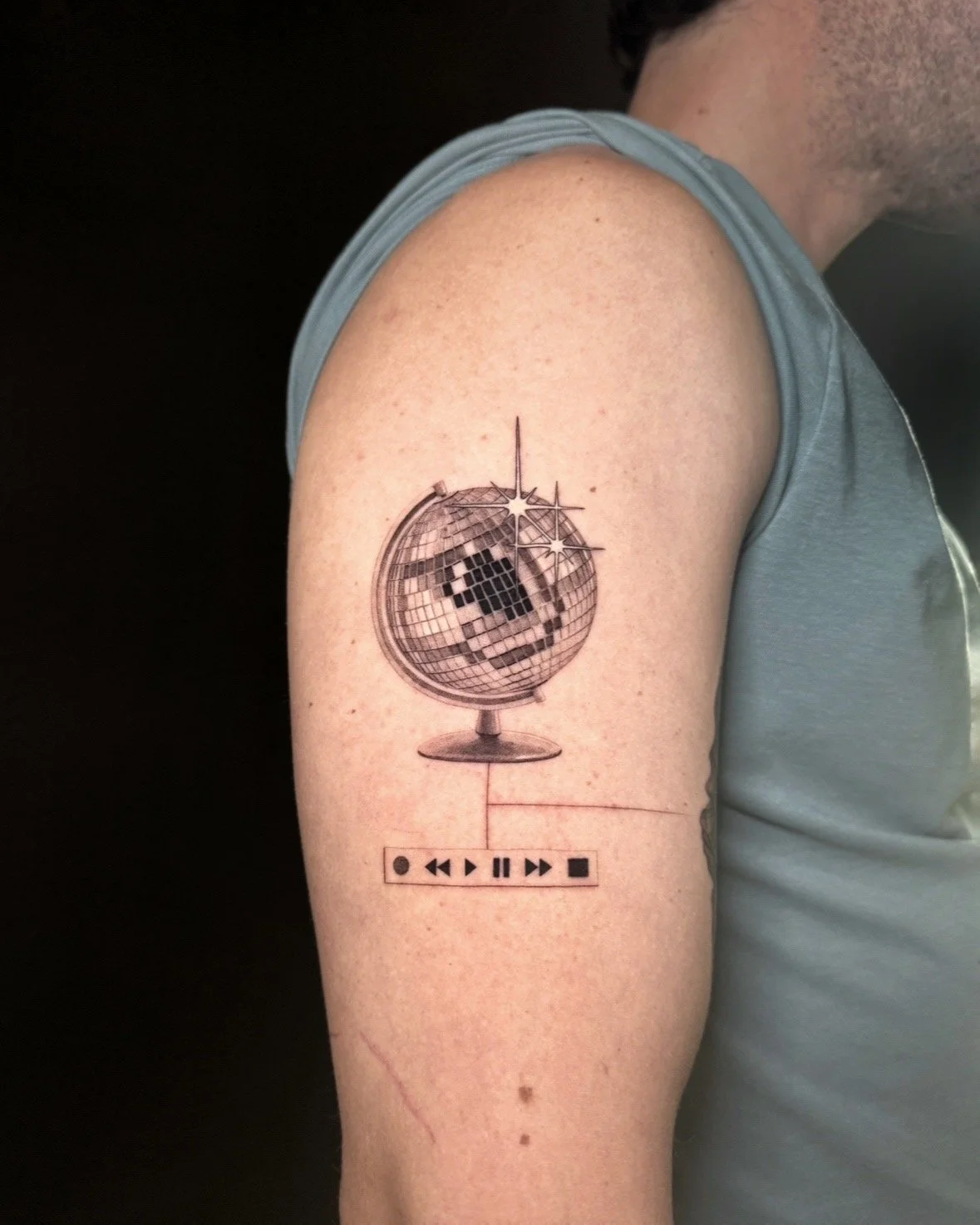 A hyper realistic tattoo done by Ihor (flowerhead.ink) on person's upper arm. Featuring a traditional globe stand with a disco ball as a planet. 