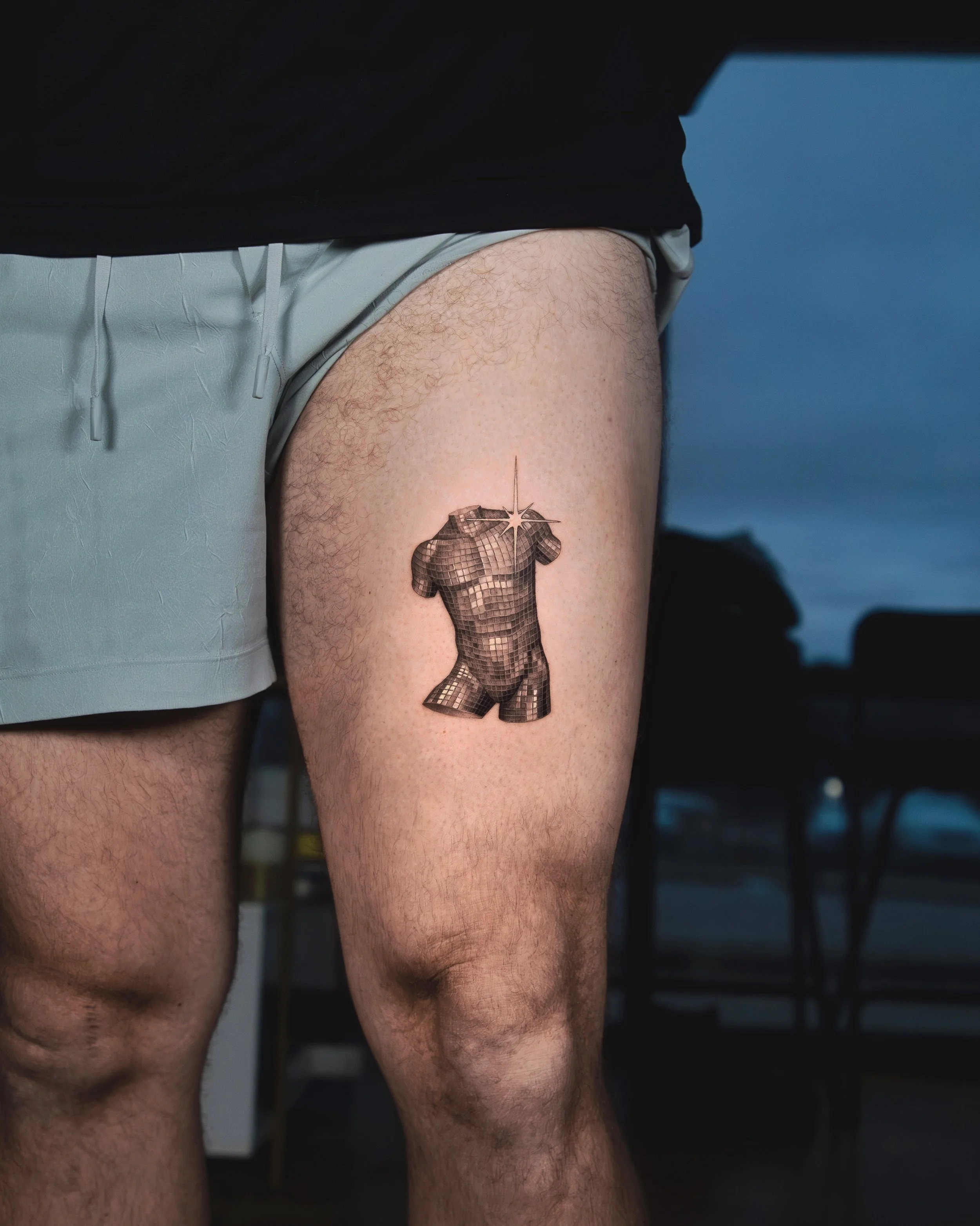 A hyper realistic custom tattoo done by Ihor (flowerhead.ink) on person's thing, above the knee. Featuring an originally designed mannequin with a disco ball texture on it. 