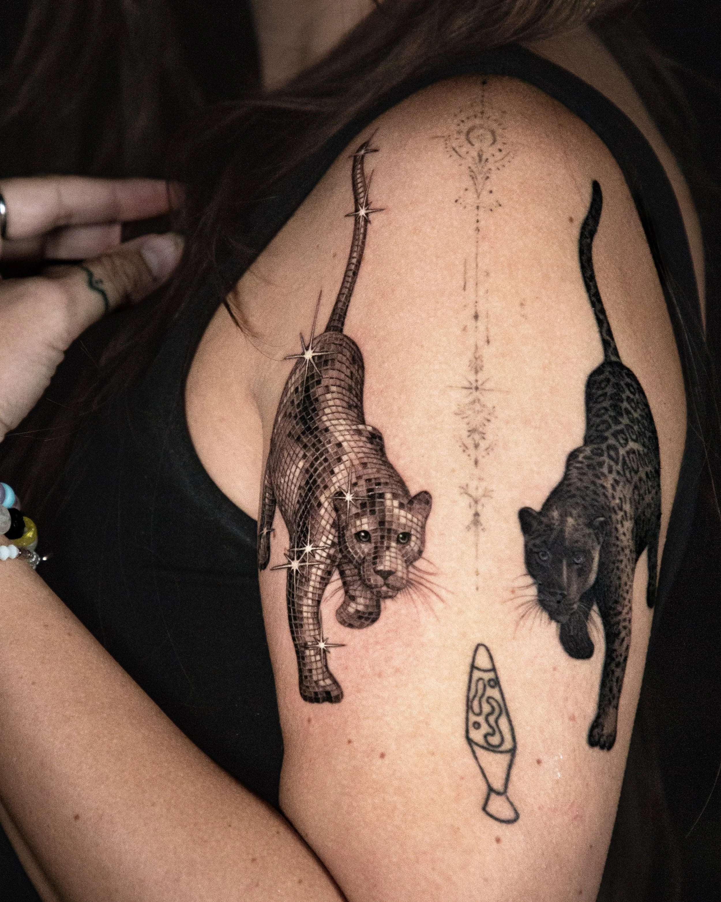 A hyper realistic custom tattoo done by Ihor (flowerhead.ink) on person's upper arm. Featuring a pair of leopards mirroring each other - one realistic and another one disco textured. 