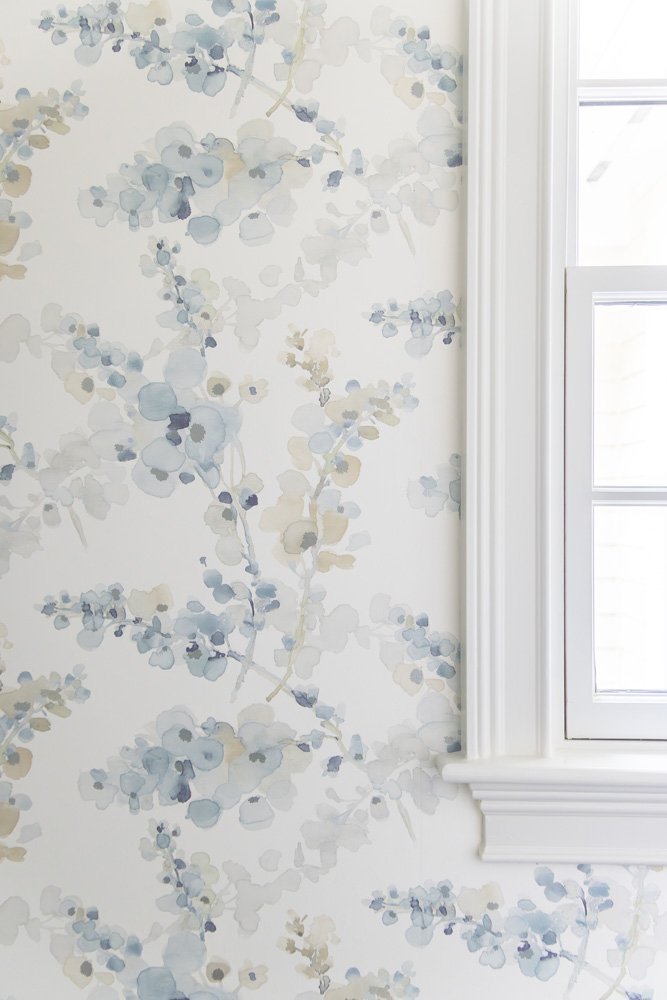 Blue and cream watercolor floral wallpaper beside a white-trimmed window