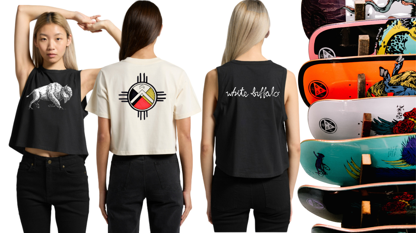 Three women wearing black and white graphic T-shirts, with a stack of skateboards with colorful designs to the right.