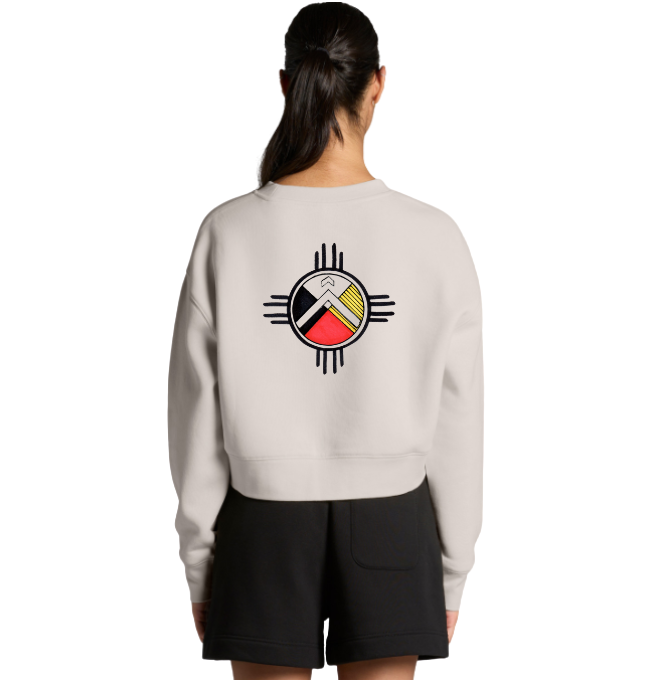Back view of a woman wearing a white sweatshirt with a colorful geometric logo on the back, and black shorts.
