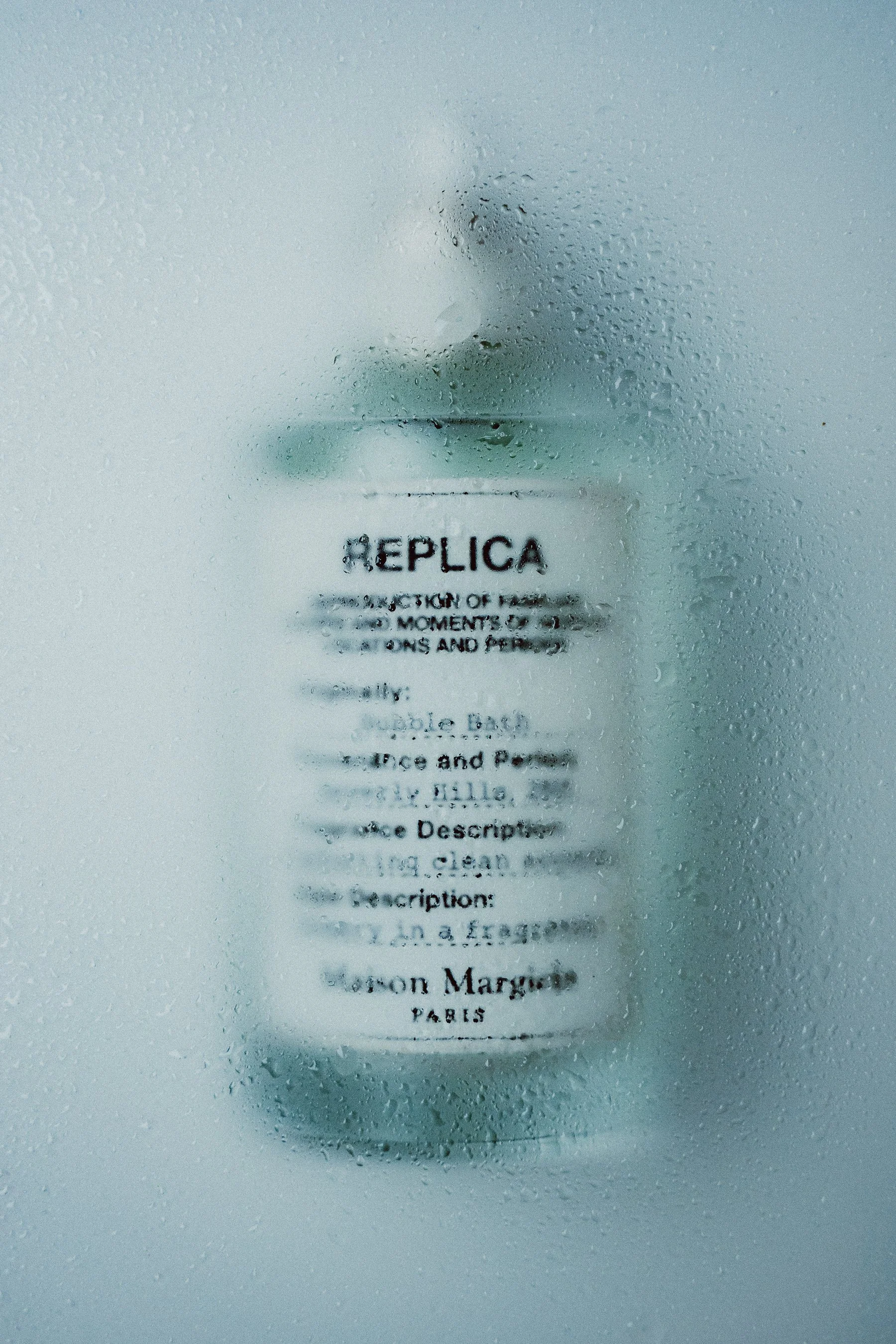 A foggy window with water droplets obscuring a blurry printed label that reads 'REPLICA' and other smaller, unreadable text.