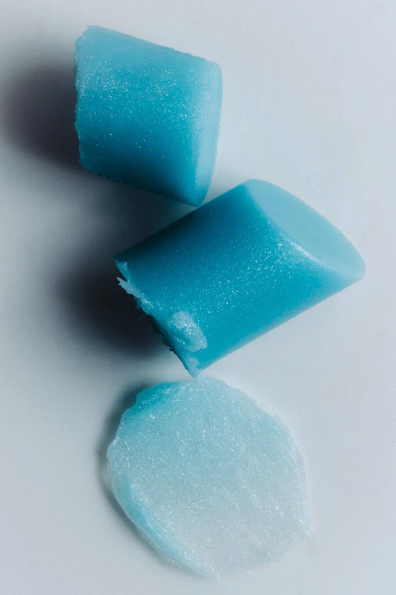 Close-up of broken blue ice cubes on a white surface.