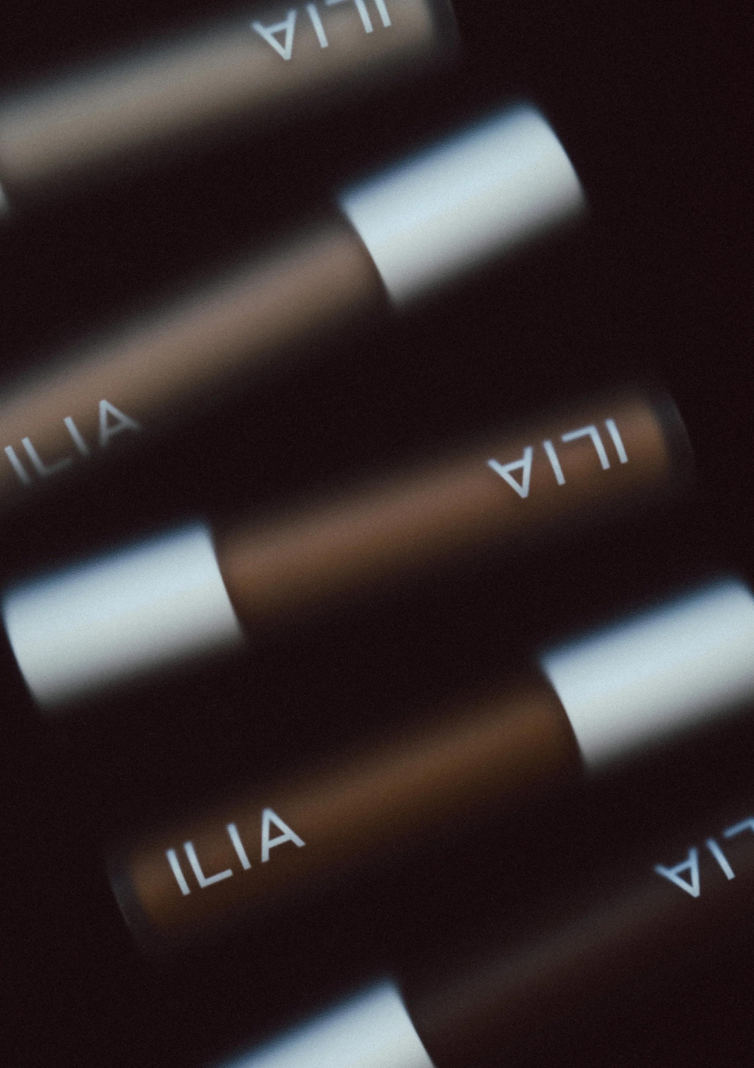 Close-up of a makeup palette with the word 'ILIA' printed on it, showing a white-cased makeup product with a matte finish.