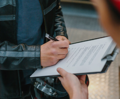 Persoon die een formulier of document invult met een pen, ondersteund door een andere persoon die de pagina vasthoudt.