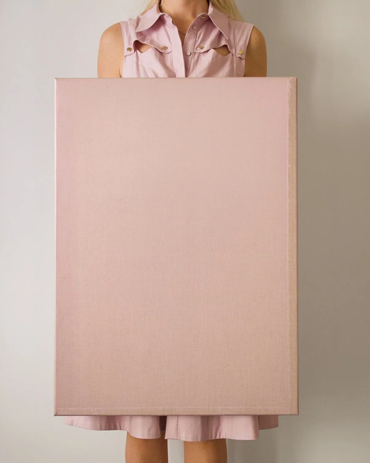 Person in pink sleeveless shirt holding a large pink box in front of their body.
