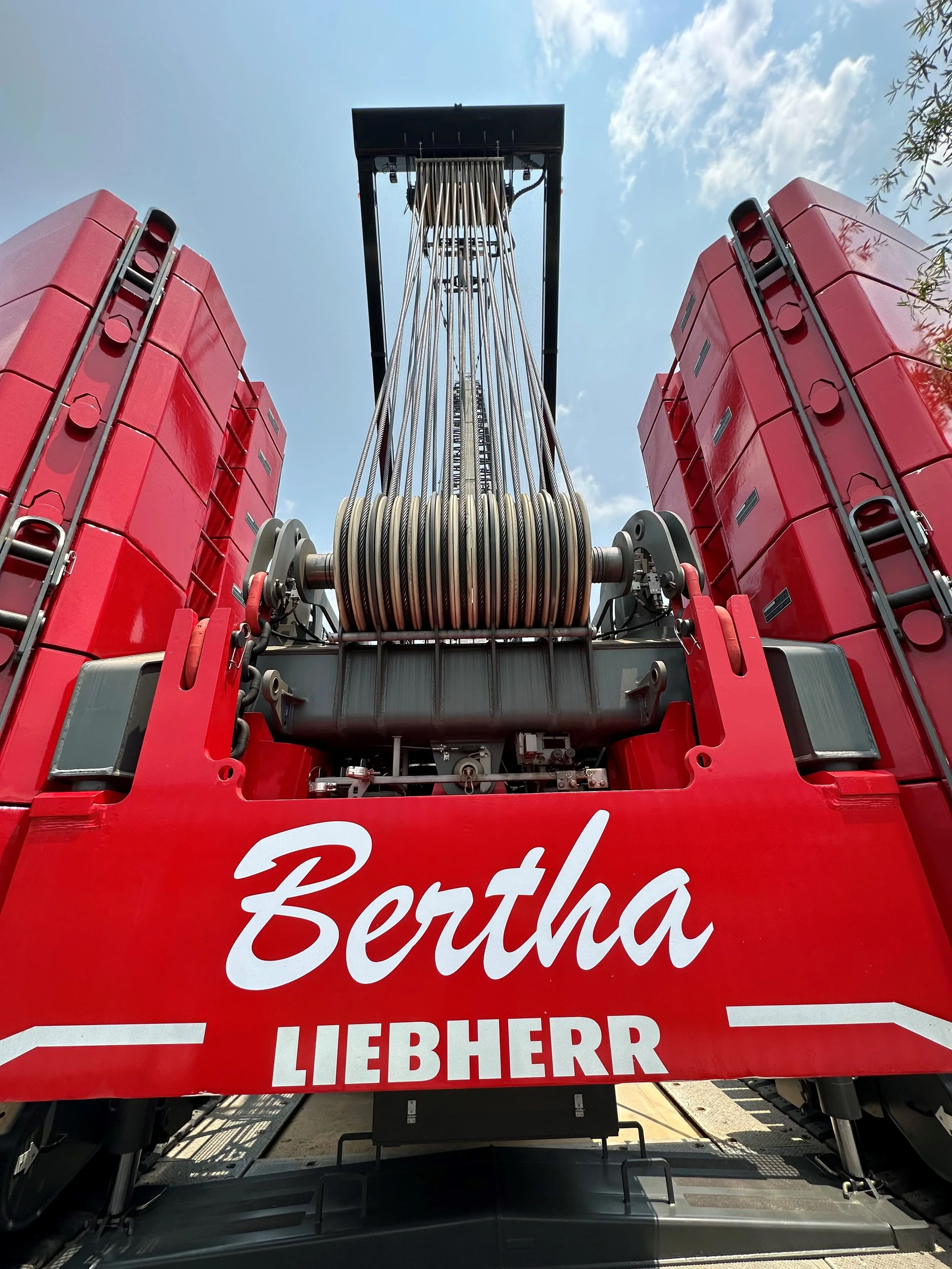 Close-up view of a fire truck with red equipment compartments, large hoses, and the name 'Bertha Liebherr' written on the front.