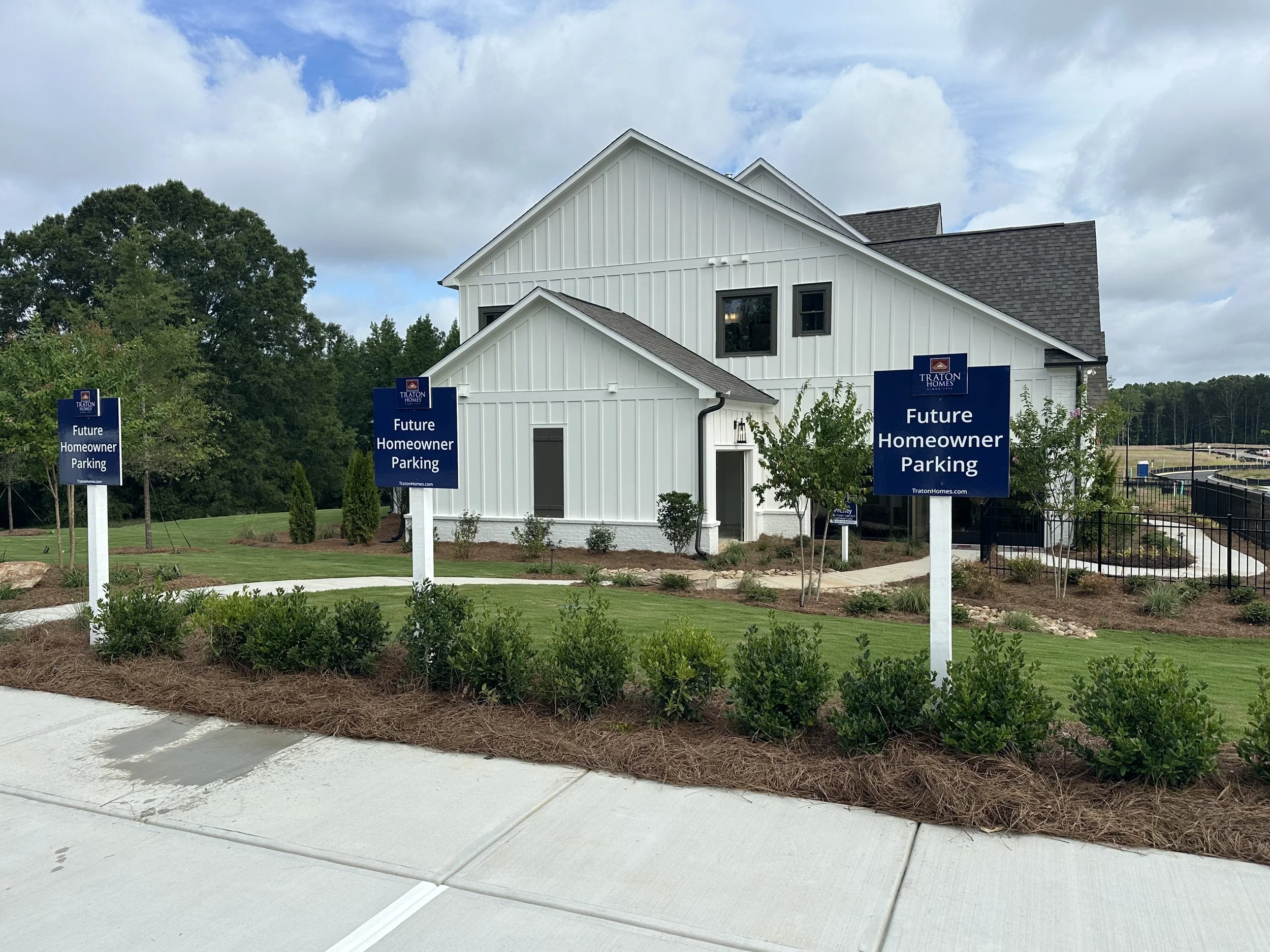 New house with white exterior, modern design, and signs indicating future homeowner parking.