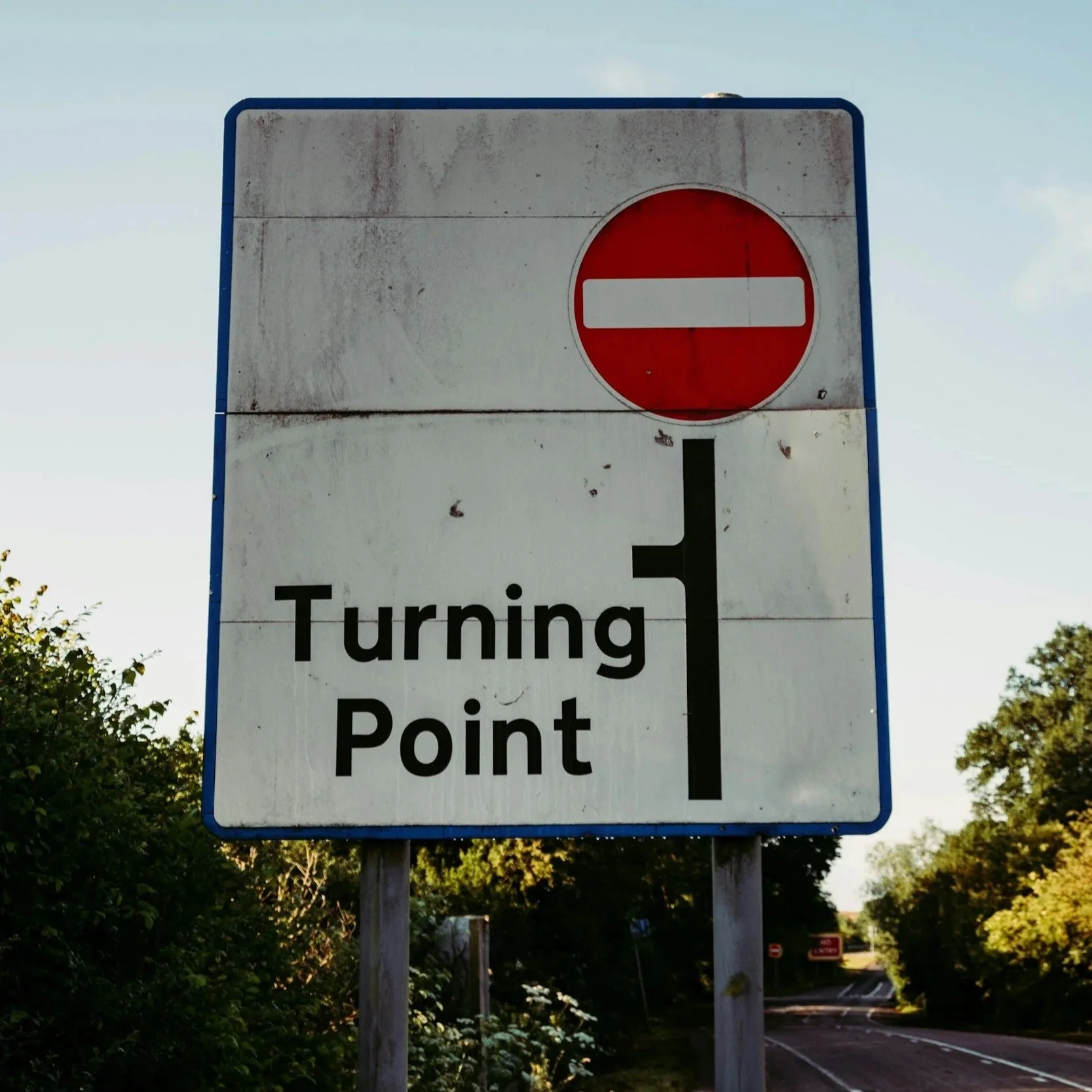 A road sign indicating a no entry with a red circle and white horizontal bar. Below, a sign states 'Turning Point' with an arrow pointing straight ahead.
