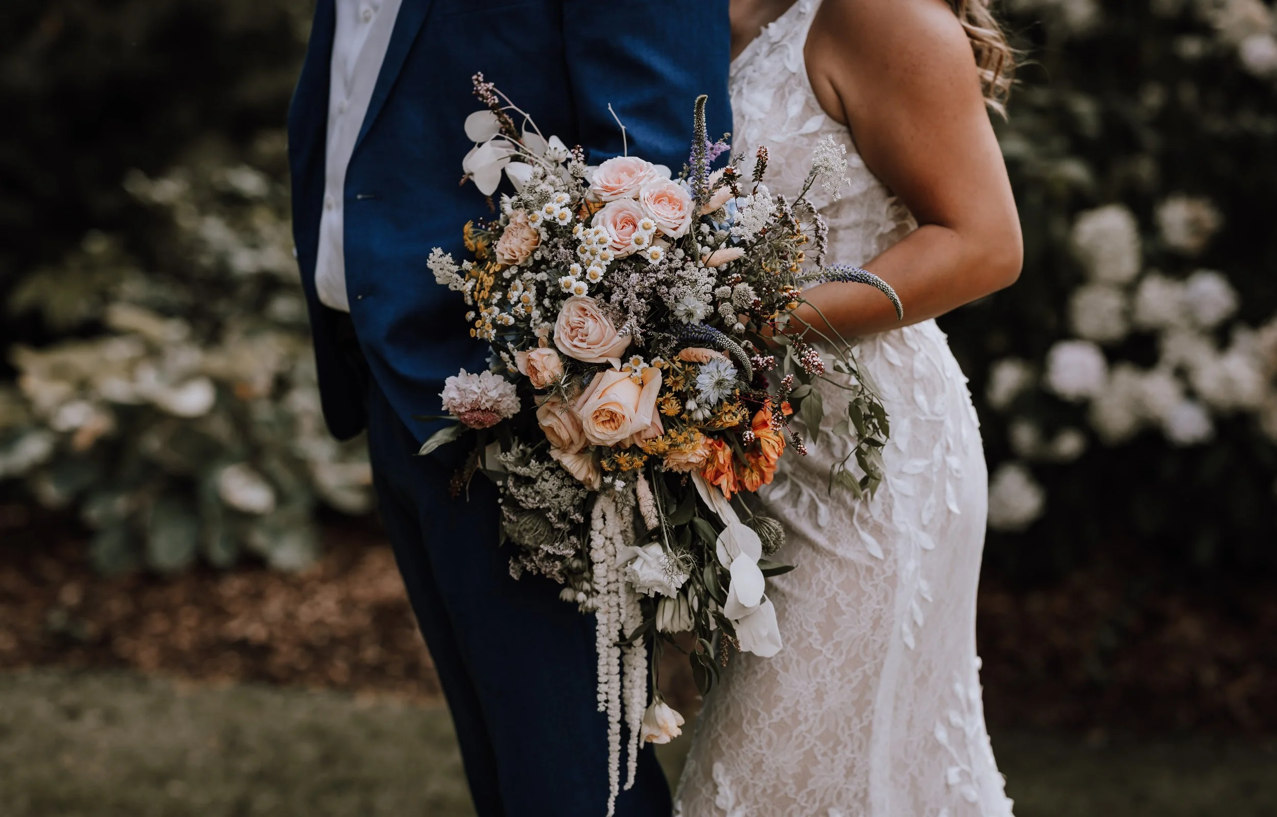 Close-up of a bride and groom sharing a moment during their wedding, with the bride holding a large, colorful bouquet of flowers.