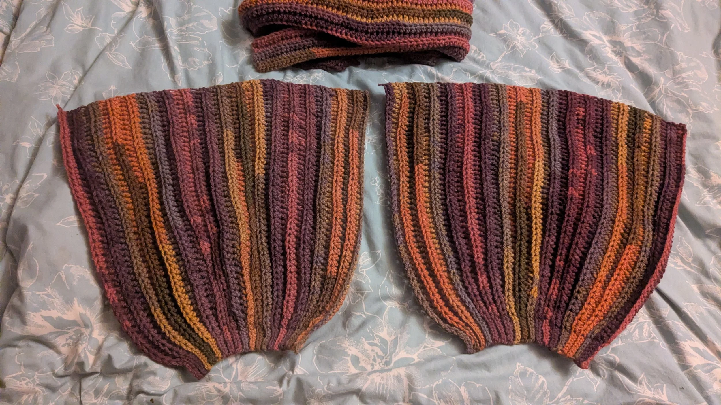 Two colorful striped crochet sleeves laid out side by side