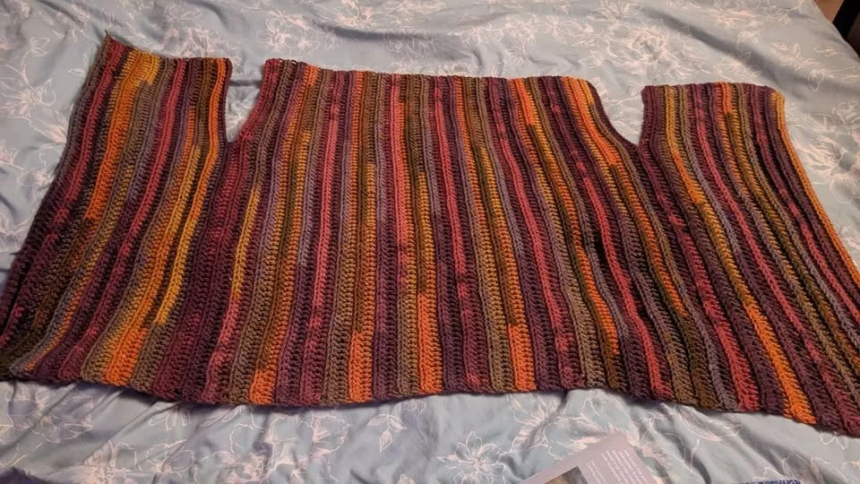 Colorful striped crocheted cardigan body with orange, pink, yellow, and brown hues.