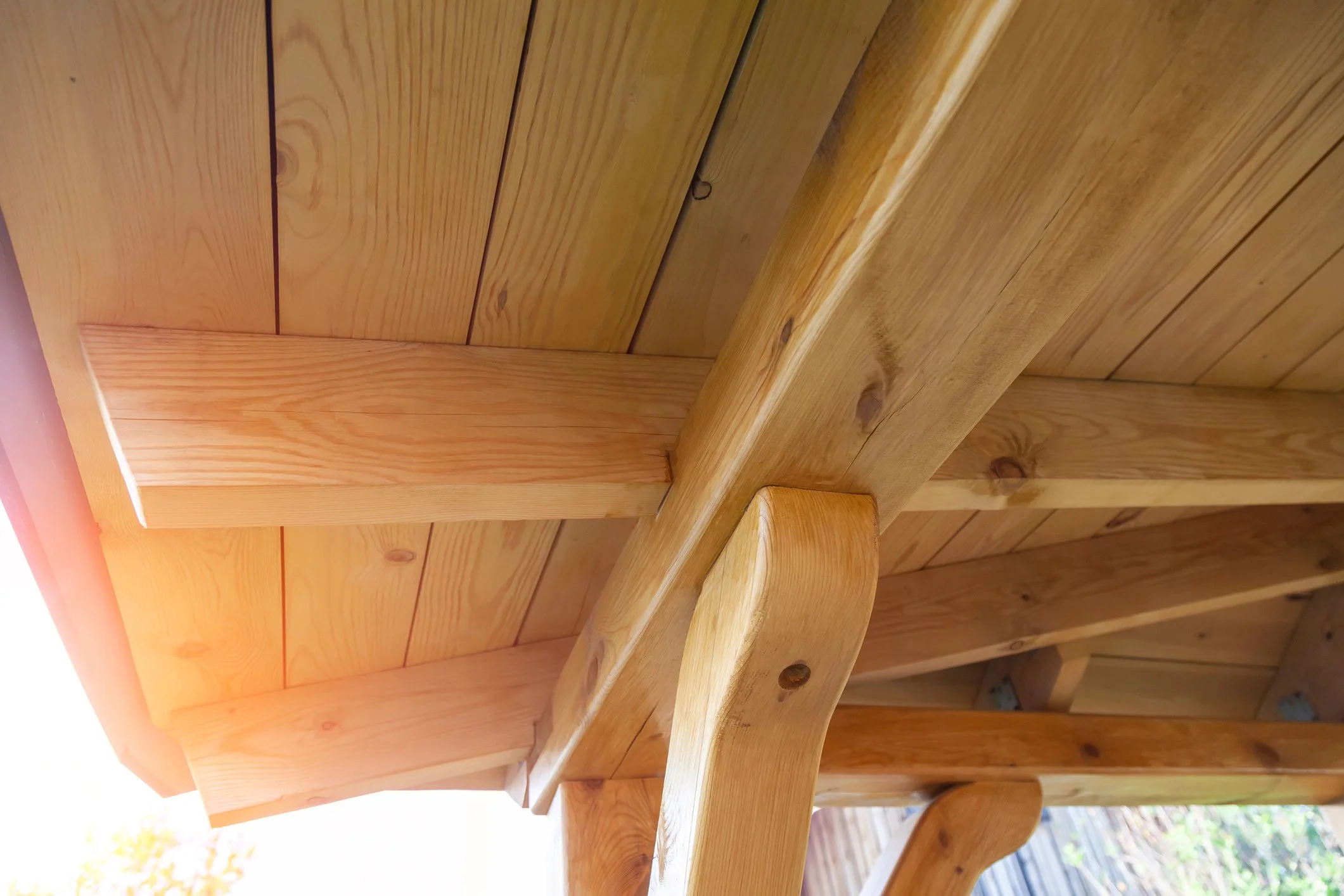 Close-up view of a wooden porch ceiling and beams, showing natural wood grain and knots.
