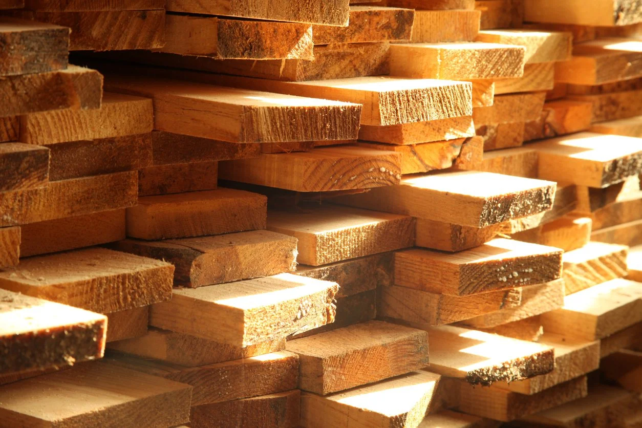 Stacked wooden planks in warm sunlight.