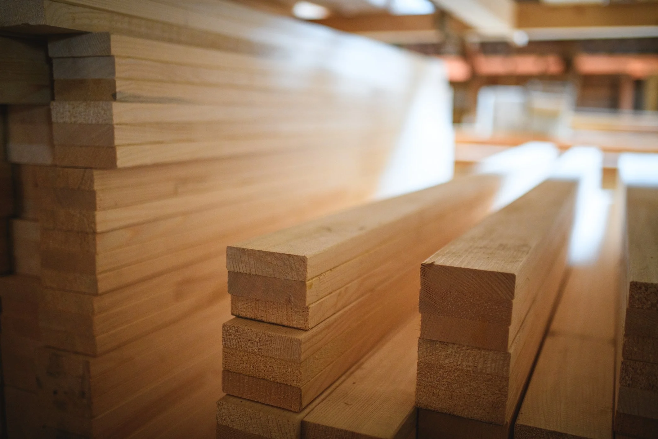 Stacked wooden planks in a woodworking or construction setting with natural light.