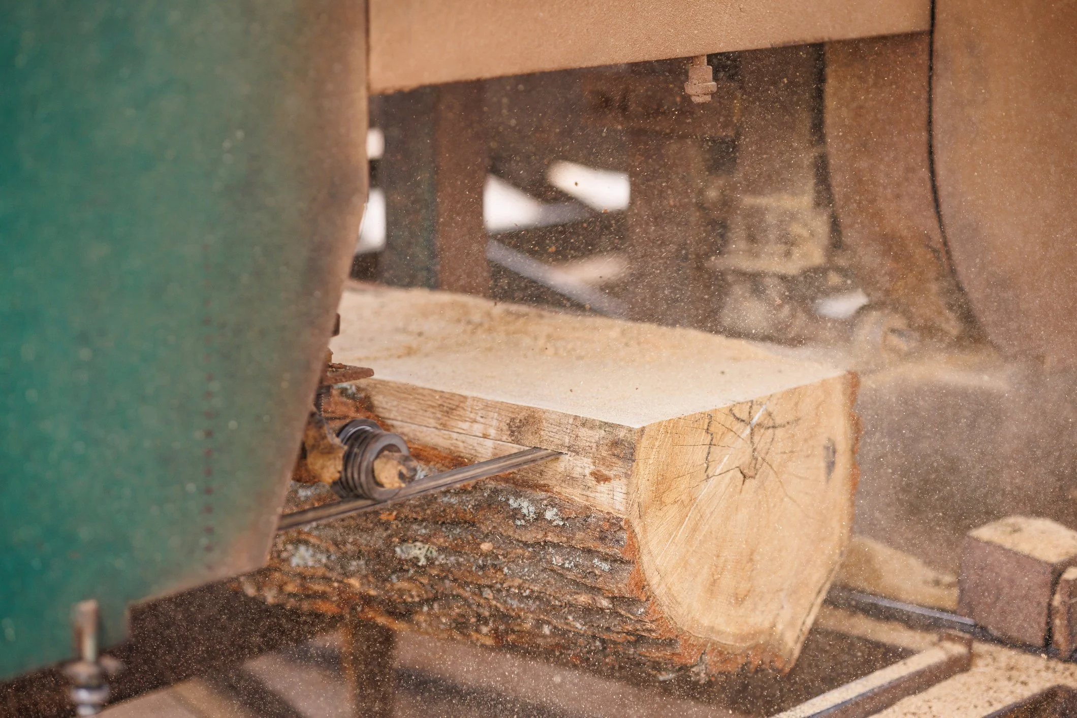 Close-up photo of a woodworking saw cutting through a piece of wood, with sawdust flying around.