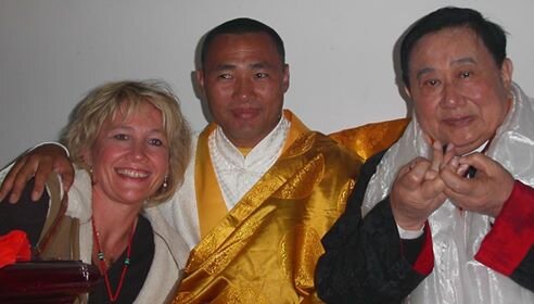 Three people smiling and posing for a photo, with one person dressed in traditional Asian attire.