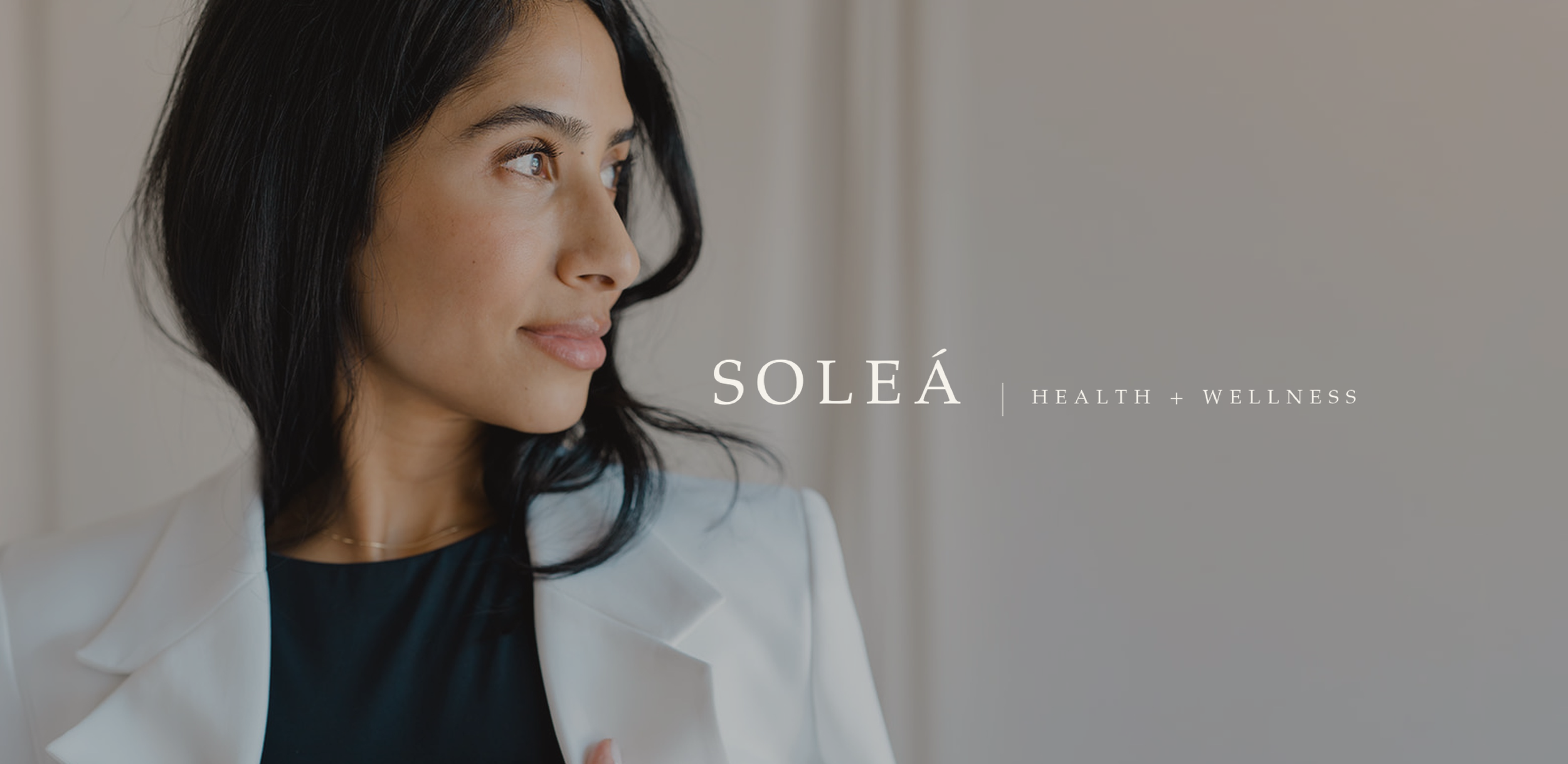 A woman with dark hair looking to the side, wearing a white jacket and black top, with the text 'SOLEÁ HEALTH + WELLNESS' written beside her.