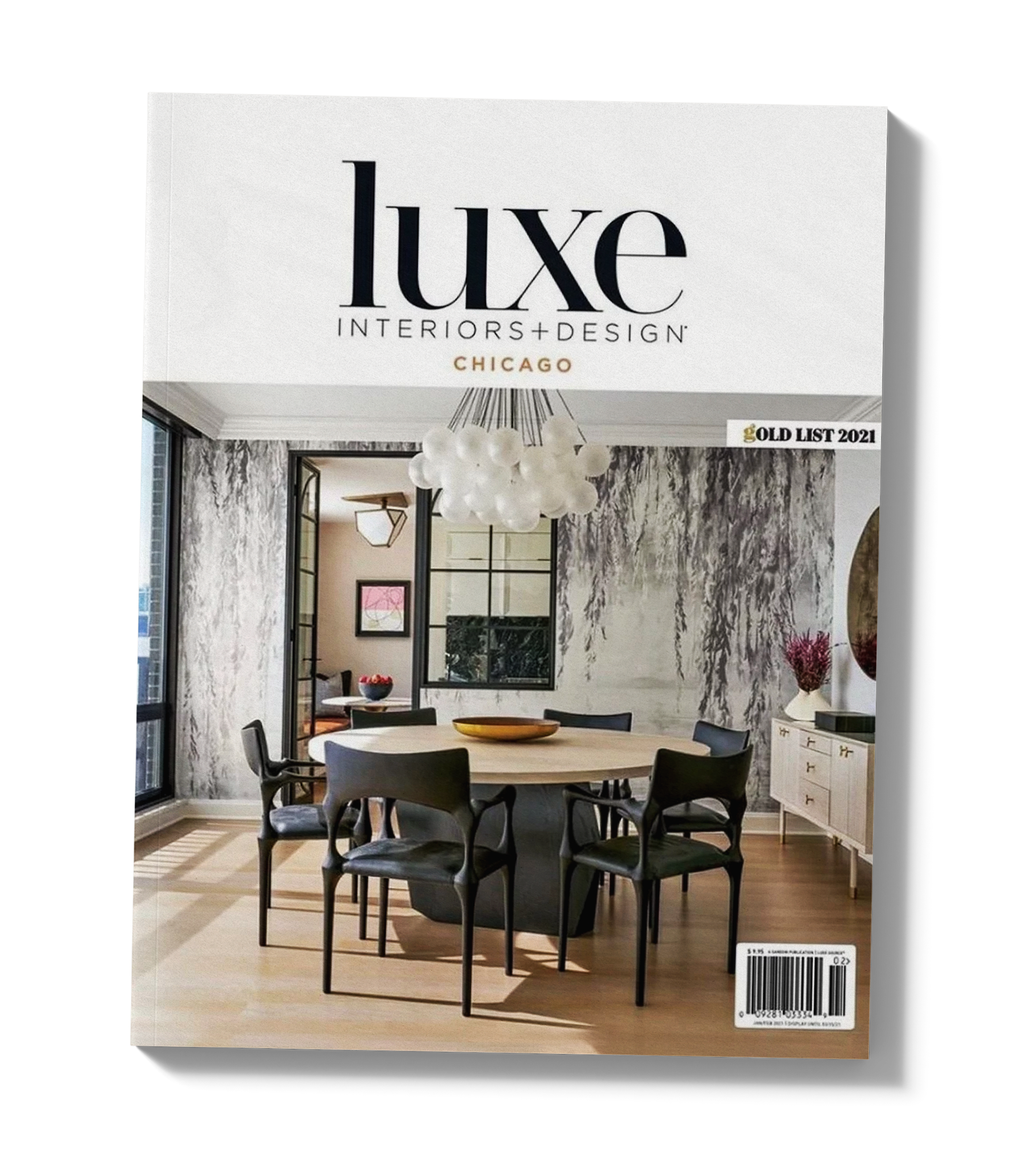 Interior of a modern dining room with a white marble table surrounded by black chairs. There is a white cabinet with gold handles, a pink flower arrangement, and a large window with blinds. A glossy white chandelier hangs above the table.