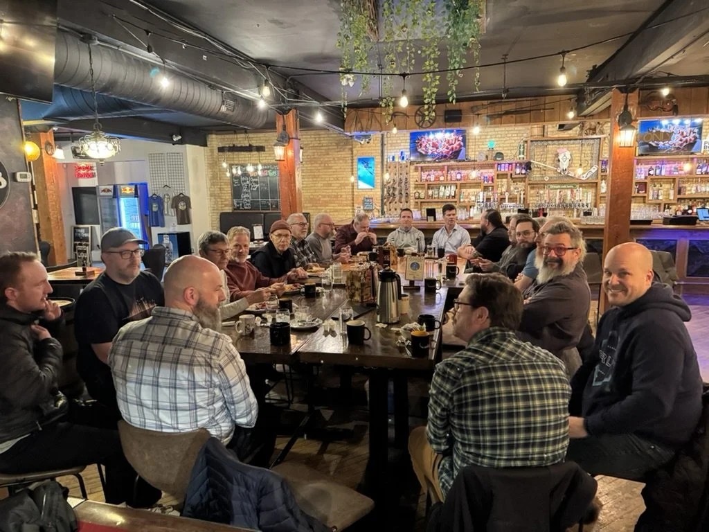 People gathered around a large table in a pub or restaurant, socializing and enjoying drinks and food.