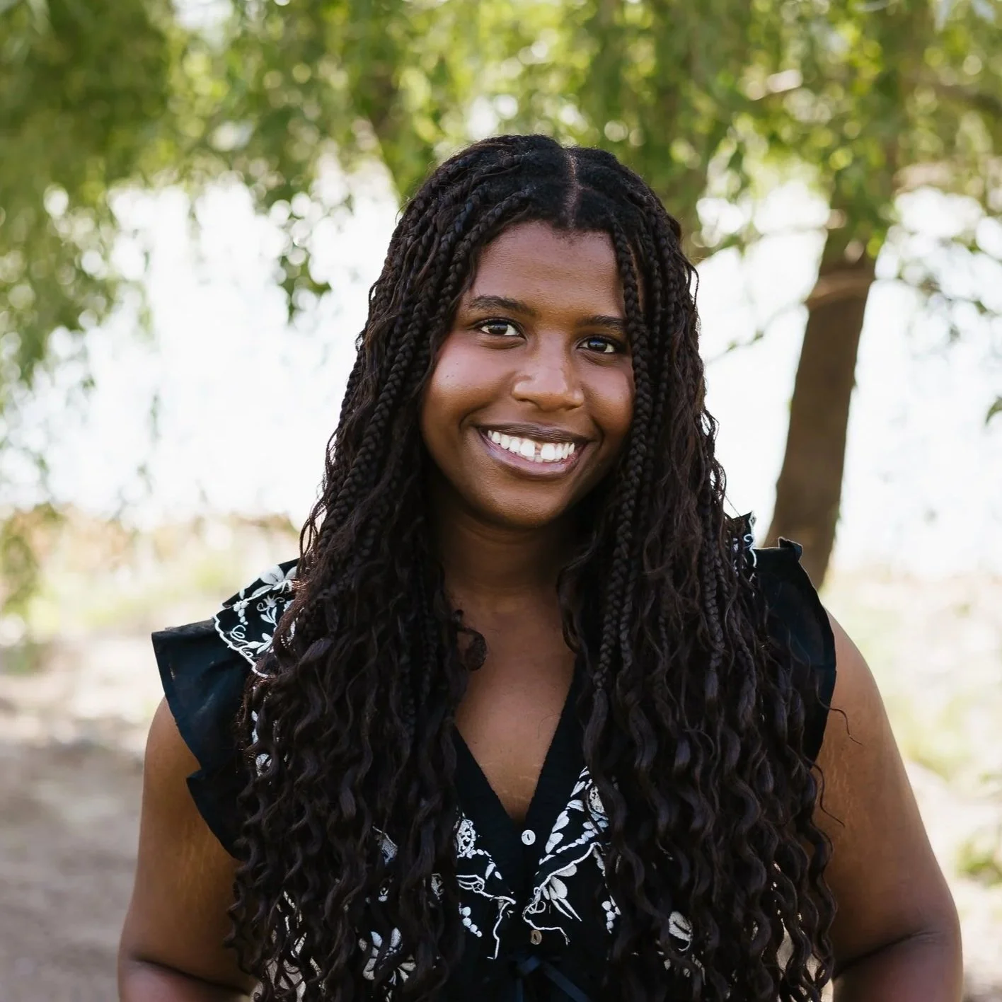 Portrait of a young woman outdoors with a tree in the background.