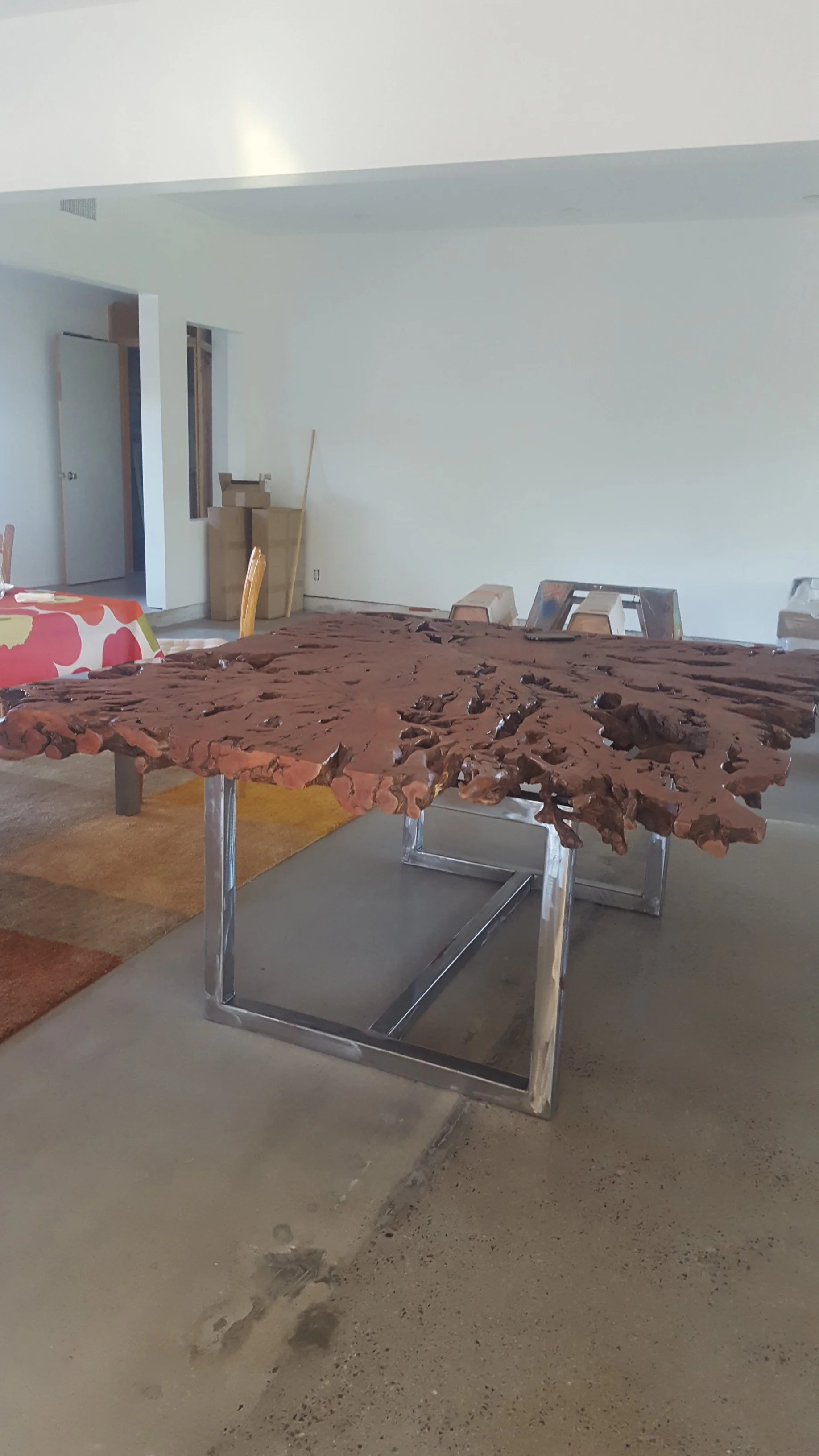 A living room features a unique live edge wood and metal table with a polished, irregular wooden top and metal legs.