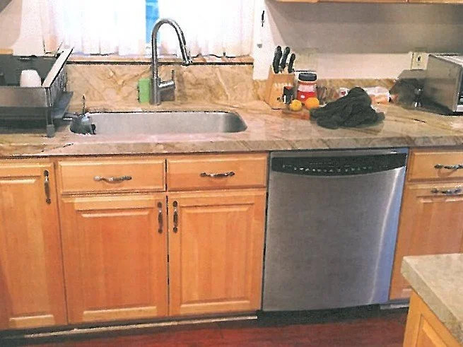 Kitchen countertop with sink, dish rack, dishwasher, and various utensils and items.