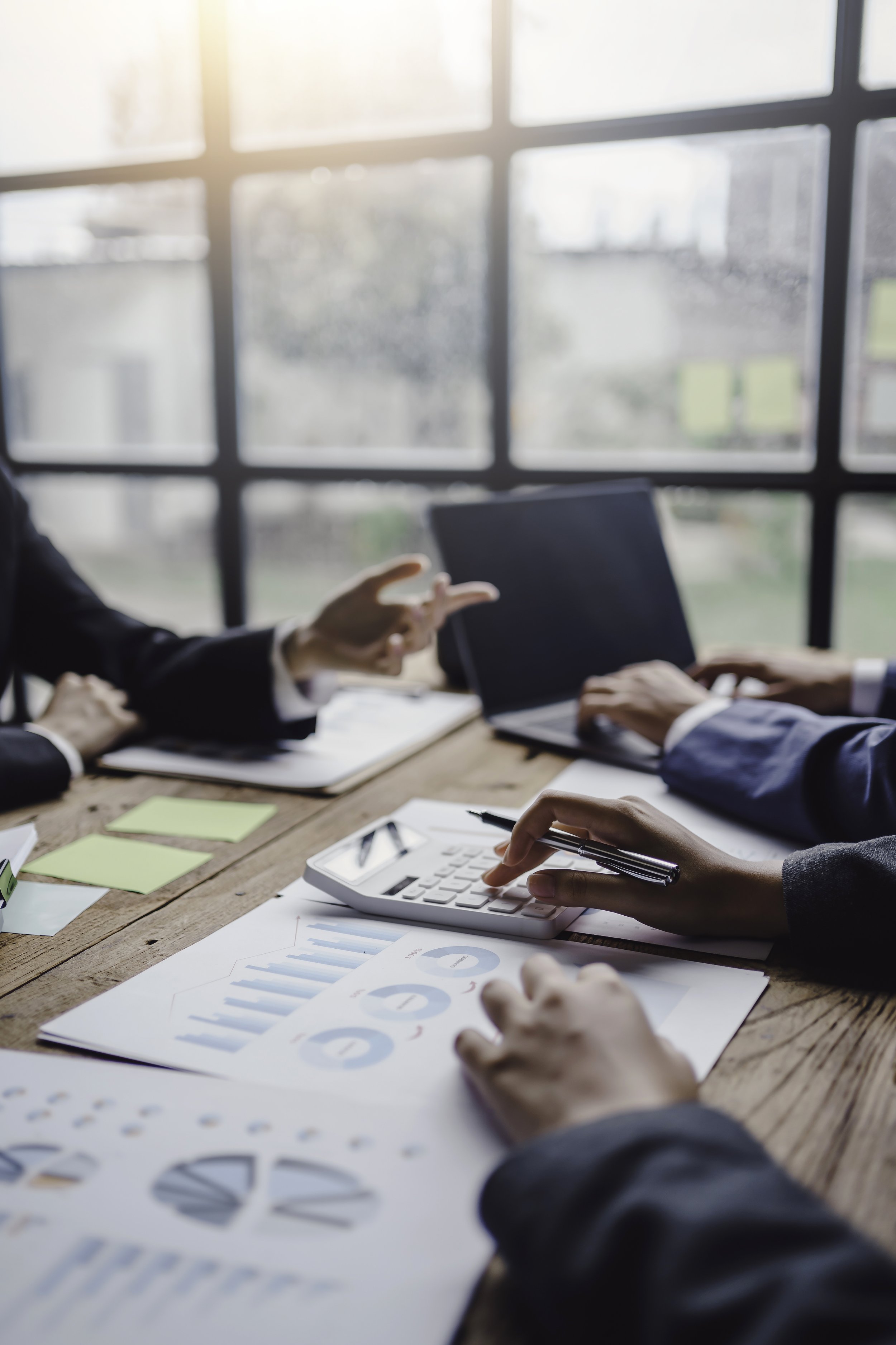 Business meeting with people discussing and analyzing charts, graphs, and documents in an office setting.