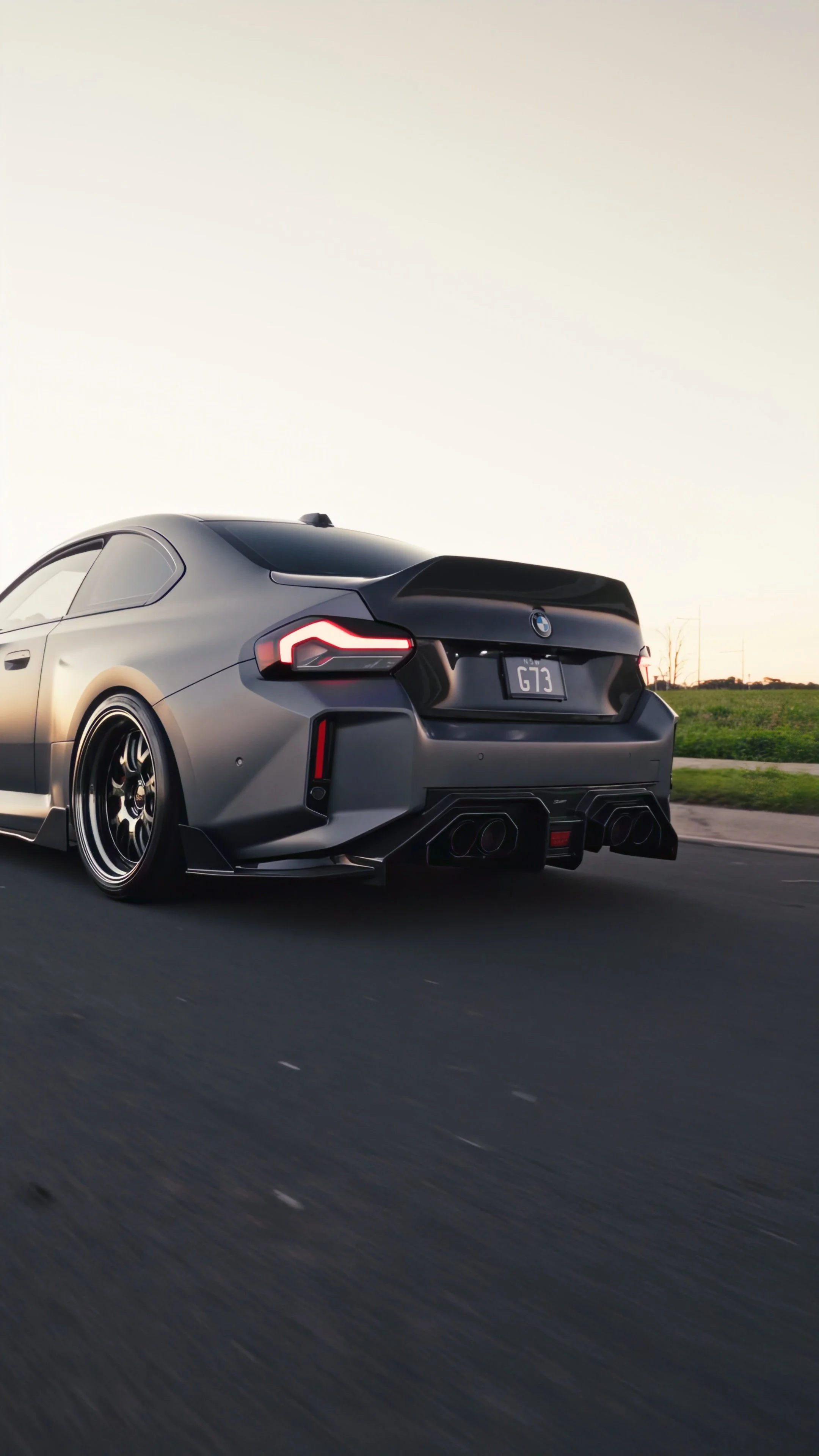 Black sports car driving on a road at sunset
