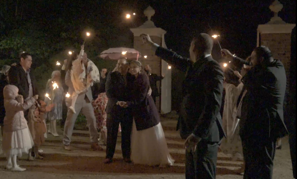 People holding sparklers at night during a celebration, with children and adults gathered outdoors.