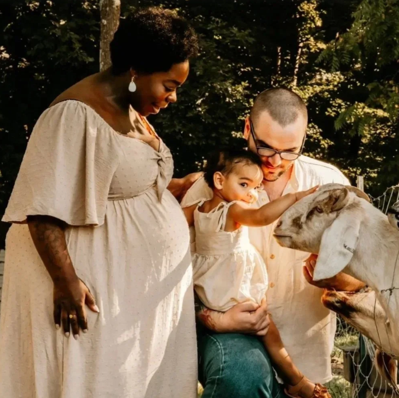 Family with goat. Family outdoors in a green setting as a young girl pets a goat.