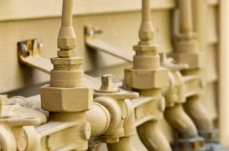 Close-up of beige plumbing pipes and valves attached to a wall.
