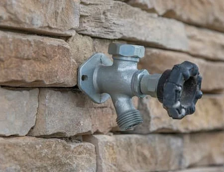 Water faucet mounted on a brick wall.