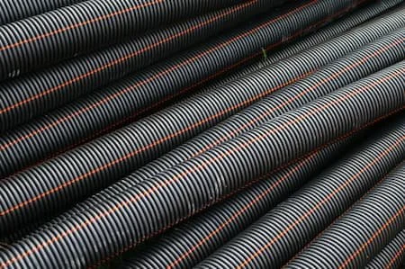 Close-up of black corrugated pipes with red and gray stripes
