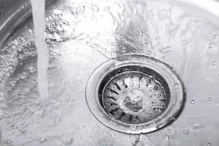 Running water coming from a faucet into a kitchen sink with a drain