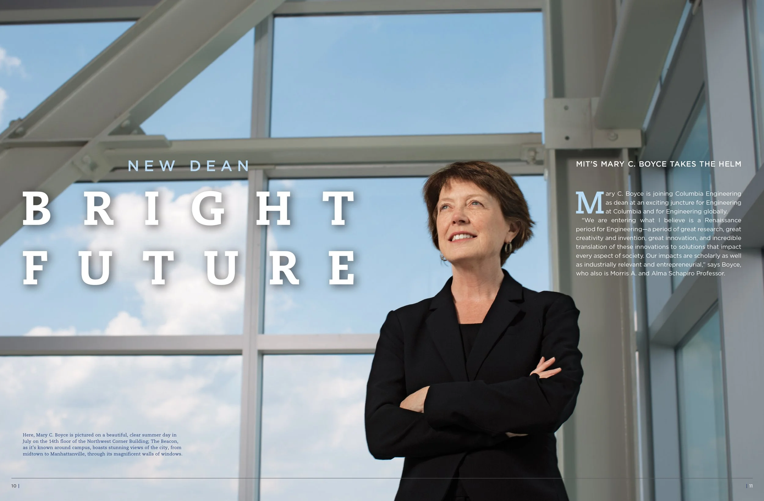 A dean standing with crossed arms in front of large windows during a clear summer day.