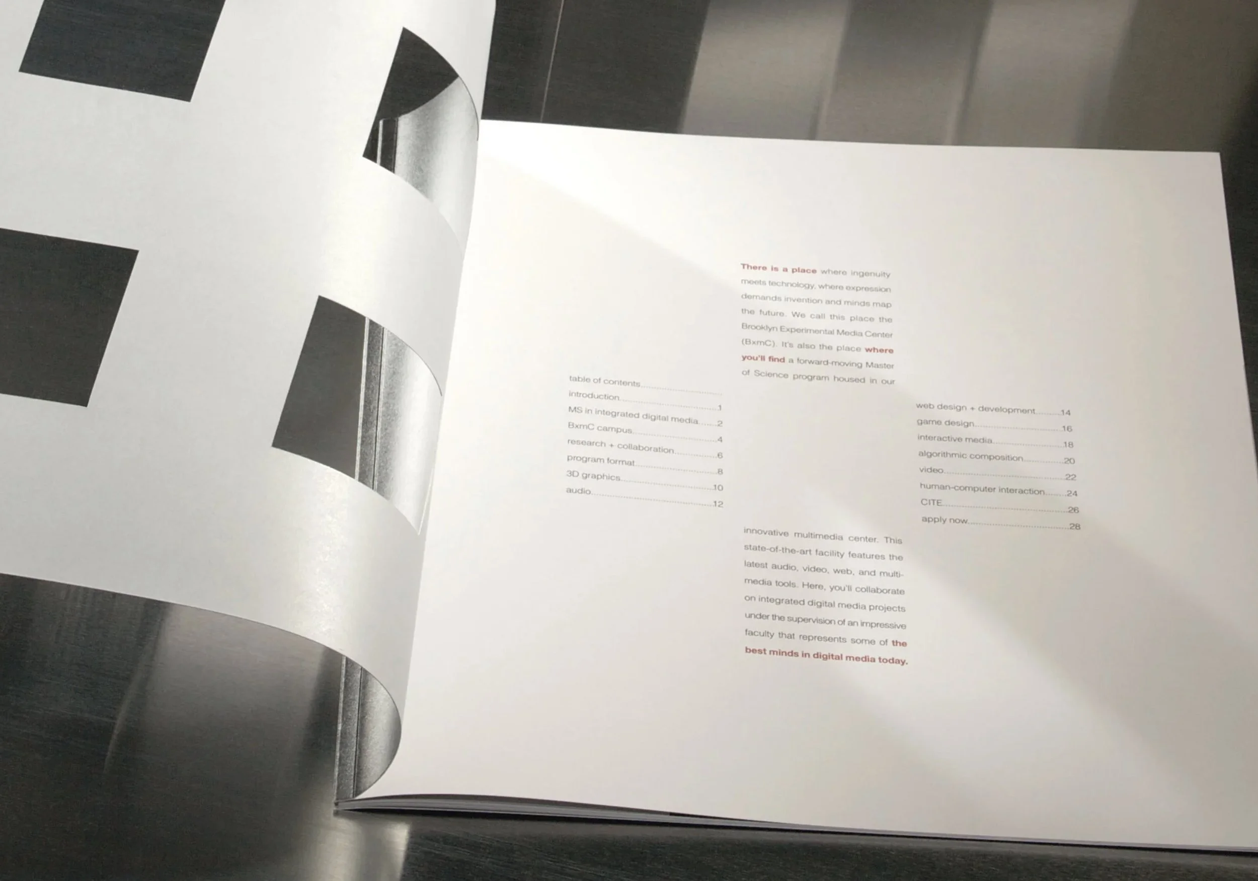 A printed book with a table of contents, partially turned pages, lying on a dark surface.