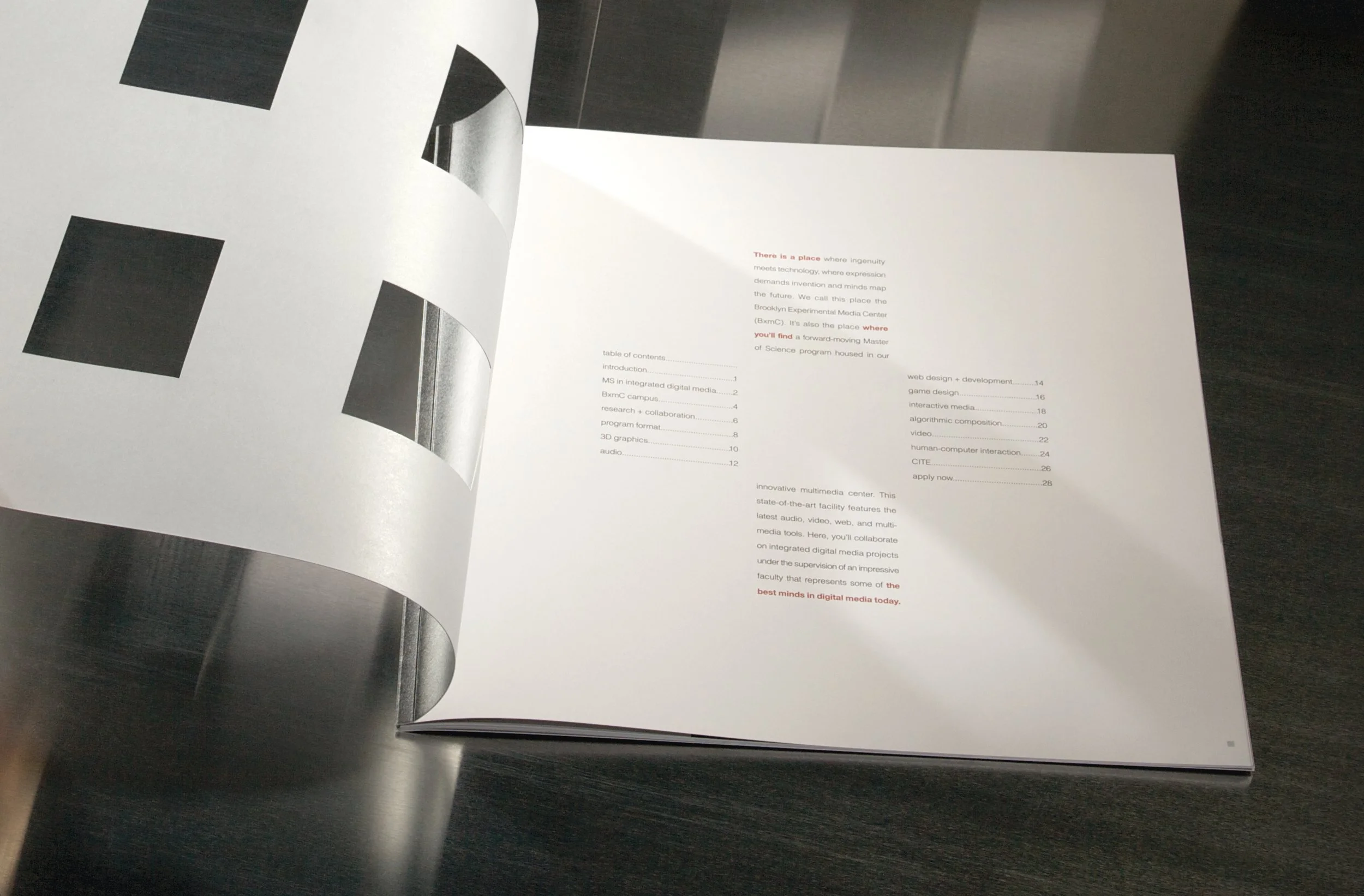 Open booklet or magazine on a dark surface, showing pages with text and some black-and-white images, possibly related to digital media or media center.