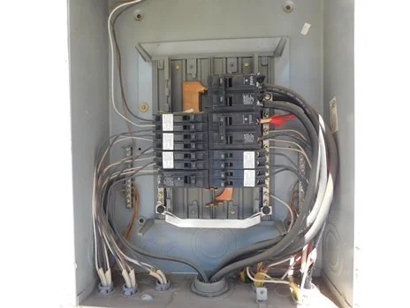 Open electrical panel with circuit breakers and wiring.
