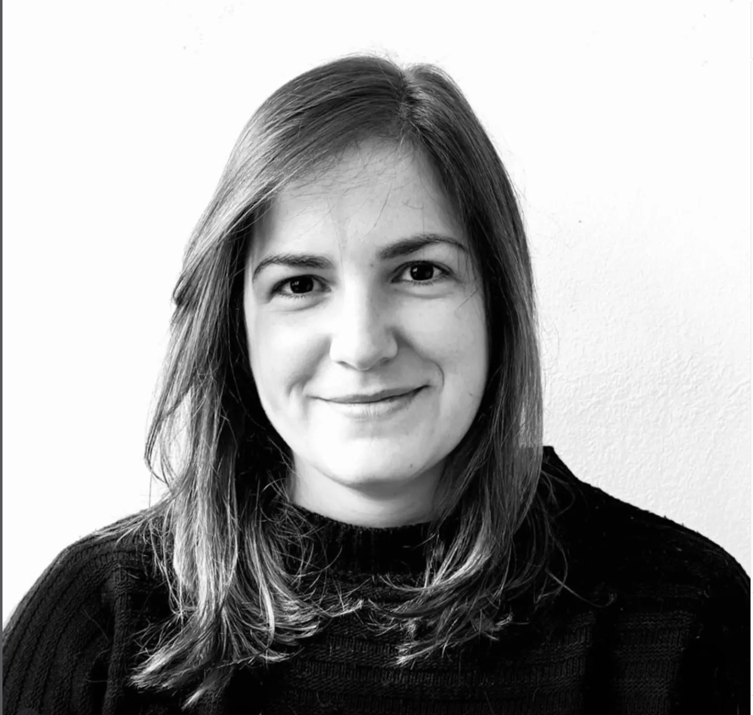 Retrato en blanco y negro de una mujer con cabello largo y suelto, sonriendo levemente, vistiendo un suéter oscuro.