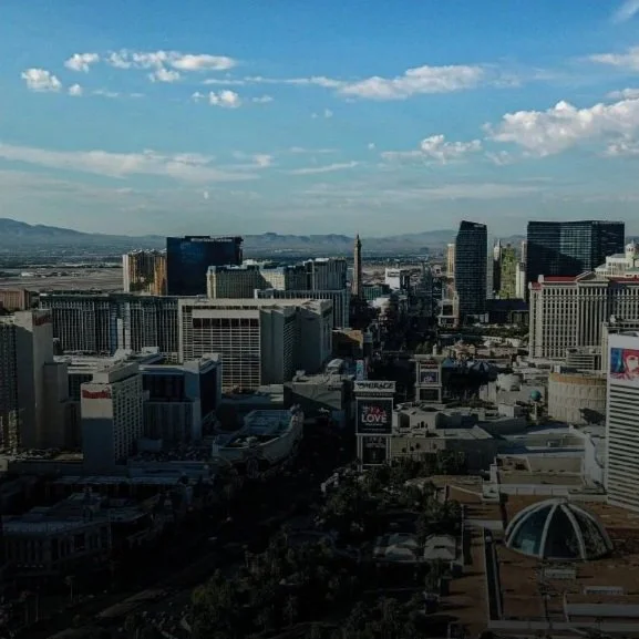 A panoramic view of a downtown cityscape with tall buildings under a partly cloudy sky.