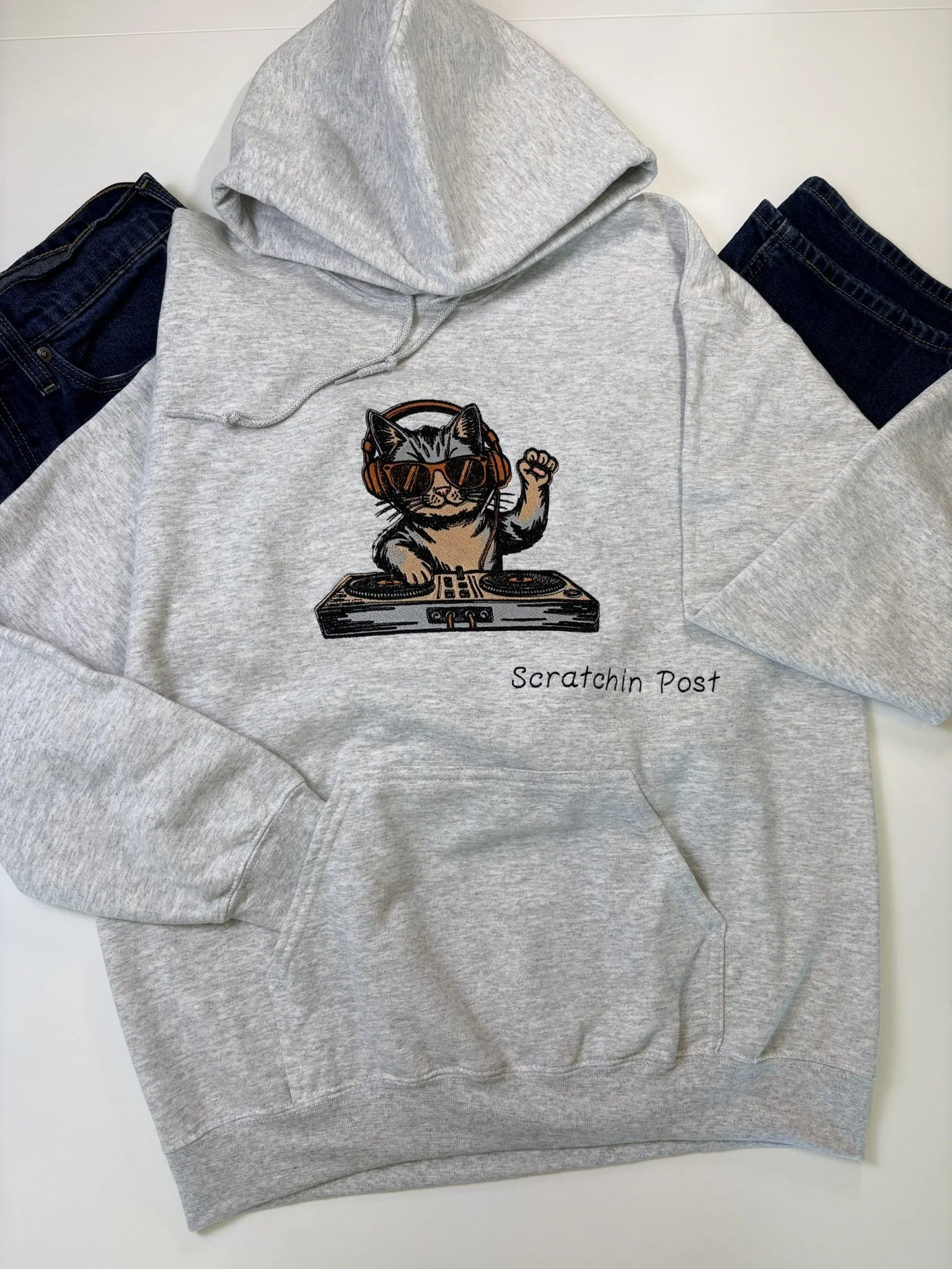 Gray hoodie with an embroidered cat wearing sunglasses and headphones, standing on a DJ turntable, with the text 'Scratchin Post' underneath.