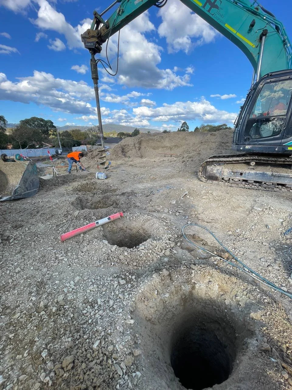 Construction site with a horizontal drilling machine and workers digging holes in the ground.