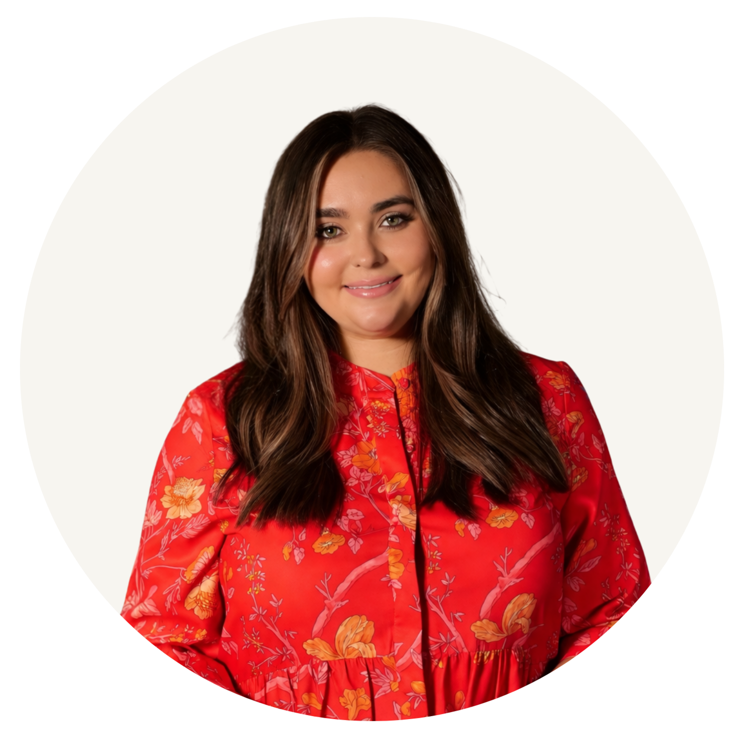 A woman with long brown hair, wearing a red floral dress, smiling, against a white background.