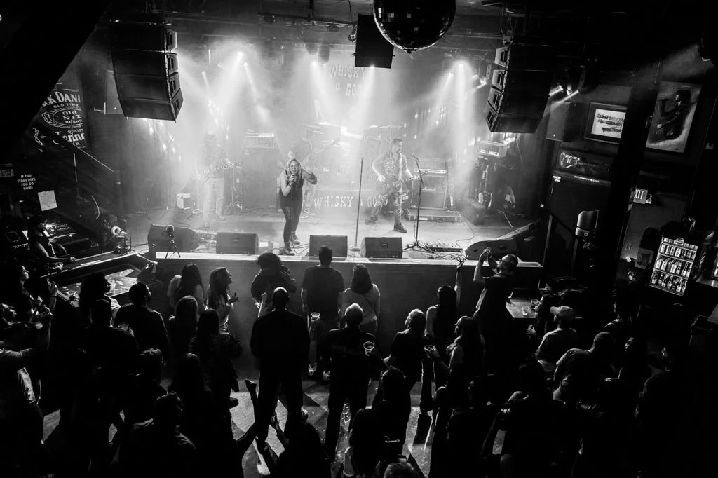 Live band performing on stage in a nightclub with audience dancing and enjoying music
