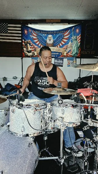 A woman playing drums in a room decorated with an American flag and patriotic banners.