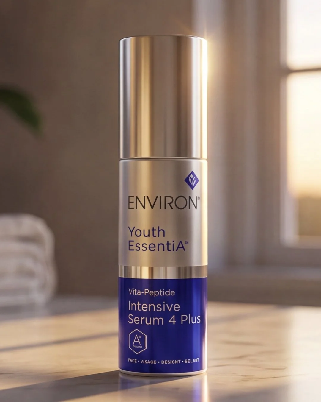 A silver and blue bottle of Environ Youth Essentia Vita-Peptide Intensive Serum 4 Plus on a wooden surface, with a blurred background of a room with window and curtains.