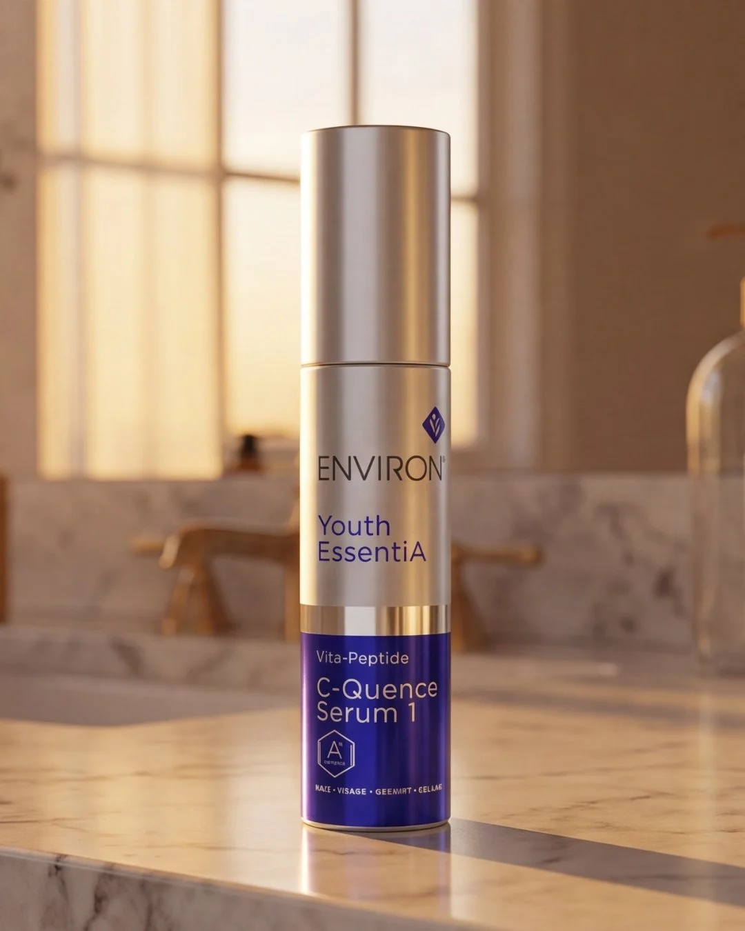 A silver bottle of Environ Youth EssentiA Vita-Peptide C-Quence Serum 1 on a marble surface with a softly lit background of a bathroom with windows.